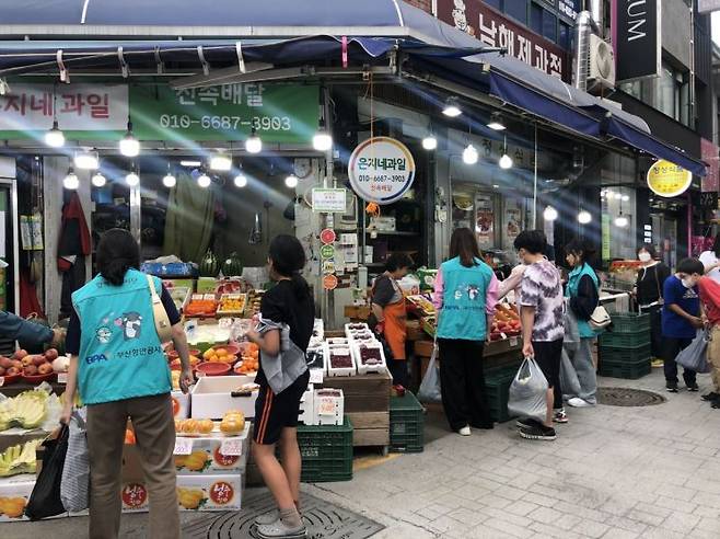 부산항만공사 직원들이 동구종합사회복지관 어린이들과 함께 전통시장에서 장보고 있다.