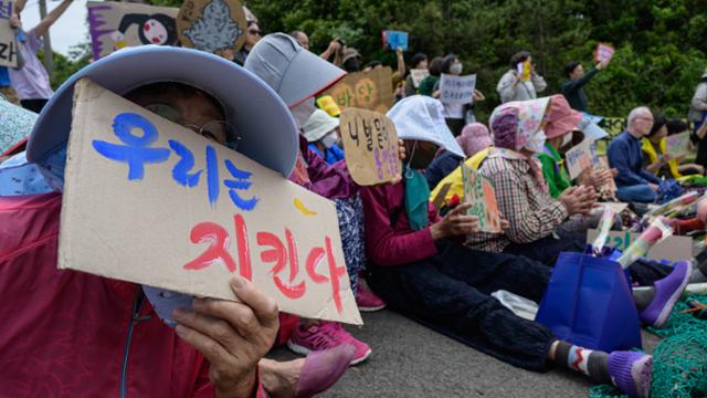 지난 19일 동부하수처리장 입구에서 열린 ‘용천동굴 지키기 범국민 운동 선포 기자회견’에서 해녀들이 얼굴을 가린 채 손팻말을 들고 있다.