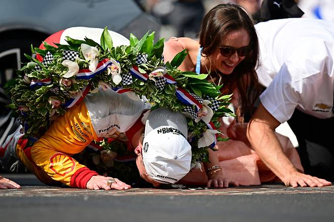 인디500 우승자 팀 펜스키의 조셉 뉴가든과 부인 애쉴리가 인디애나폴리스 모토 스피드웨이 트랙의 벽돌에 키스를 하고 있다. 인디애나폴리스|USA TODAY Sports연합뉴스