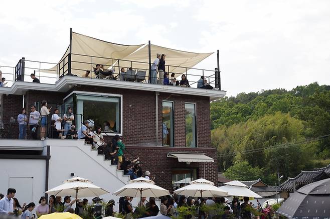 Visitors sit on the rooftop and stairs of a nearby cafe to get a better view of the fireworks. (Lee Si-jin/The Korea Herald)