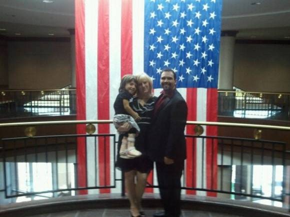 나탈리아 그레이스를 안고 성조기 앞에서 포즈를 취한 크리스틴과 마이클 바넷 부부. 디스커버리 제공