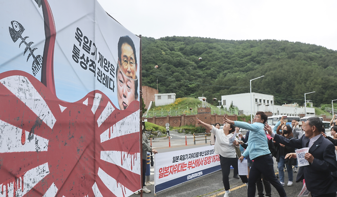 6.15남측위부산본부 회원들이 30일 오전 부산 남구 해군작전사령부 앞에서 일본 욱일기의 일종인 자위함기를 게양한 해상자위대 호위함 하마기리 함의 부산 해군작전기지 입항을 규탄하며 욱일기가 그려진 현수막에 계란을 던지는 퍼포먼스를 하고 있다. / 사진=연합뉴스