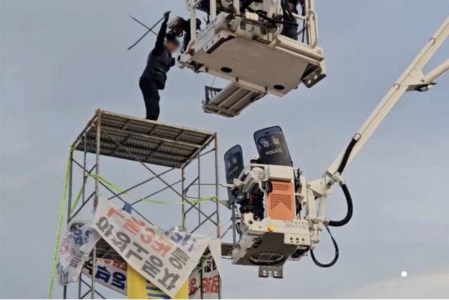 경찰-노조 간부 '초긴장 대치'31일 전남 광양제철소 인근 도로에서 높이 7m 망루를 설치해 고공농성을 벌인 한국노총 금속노련 간부가 체포에 나선 경찰관에게 막대를 휘두르며 저항하고 있다. 전남경찰청 제공