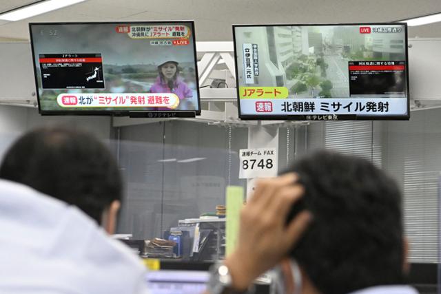 31일 일본 도쿄에서 주민들이 TV 화면에 뜬 북한 미사일 관련 속보를 바라보고 있다. 이날 오전 일본 정부는 전국순시경보시스템(J-ALERT)을 통해 대피 명령을 내렸지만 약 30분 만에 해제했다. 도쿄=AP 연합뉴스