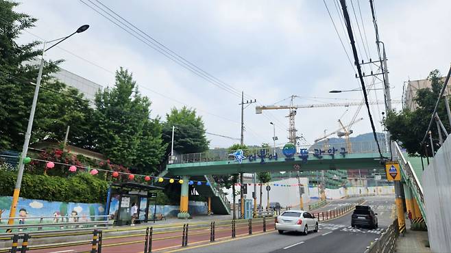 서울신우초등학교 정류장에서 바라본 '서울대벤처타운 푸르지오' 공사현장 모습. 그 앞으로 육교가 보이고, 왼쪽으로는 신우초등학교가 있다./조은임 기자