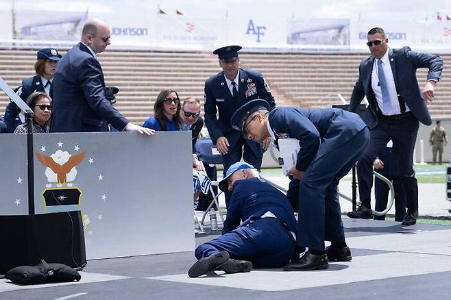 조 바이든 미국 대통령이 1일 공군사관학교 졸업식 연단에서 넘어져 부축을 받고 있다. 콜로라도스프링스/AFP 연합뉴스