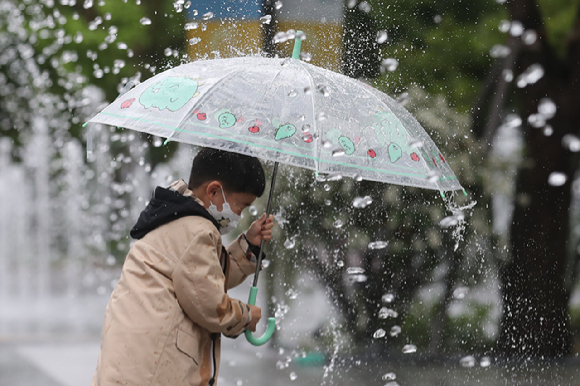 어린이날인 5일 오전 서울 종로구 광화문광장에서 어린이가 우산을 쓰고 분수대 사이를 지나가고 있다. [사진=뉴시스]
