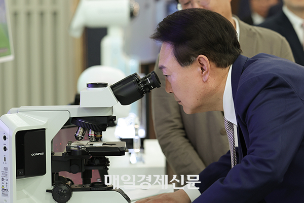 President Yoon Suk Yeol looks through a microscope in Seoul on June 1. [Photo by Lee Seung-hwan]