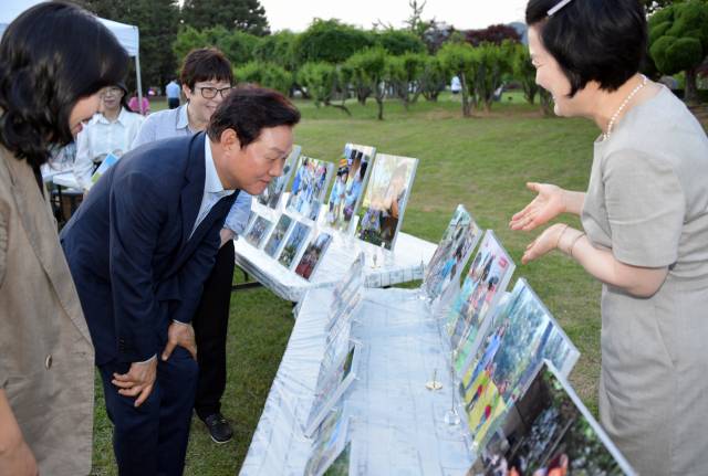 박완수 경상남도지사가 2일 도청 잔디광장에서 개최된 보육교직원 연수회에 참석해 보육교직원의 안내를 받으며 아이들의 작품을 웃으며 보고 있다. /사진제공=경남도