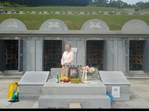 "北 조카 꼭 다시 만났으면"      (서울=연합뉴스) 지난 1일 전북 군산의 추모시설에서 '납북 고교생' 김영남씨의 누나 영자씨가 어머니 영전에 '김영남·메구미 자 김은경' 글귀가 쓰인 꽃바구니를 올리고 제단 뒤에 서 있다. [김영자씨 제공]