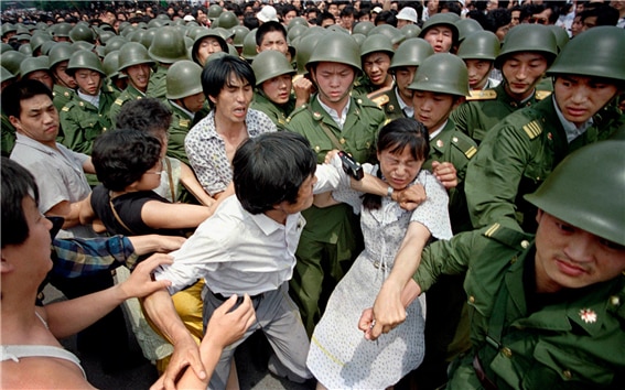 1989년 6월 3일 인민대회당 앞에서 군인들에 둘러싸인 채 저항하는 시민들. 한 여인의 손목을 잡아끄는 군인을 한 시민이 막아서고 있다. /Jeff Widener/AP