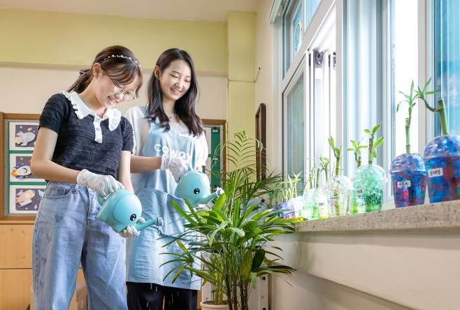 지난 1일 코웨이 청정학교 교실숲 4호로 선정된 서울당현초등학교 한 교실에서 코웨이 임직원과 초등학생이 공기정화식물에 물을 주고 있다. 코웨이 제공
