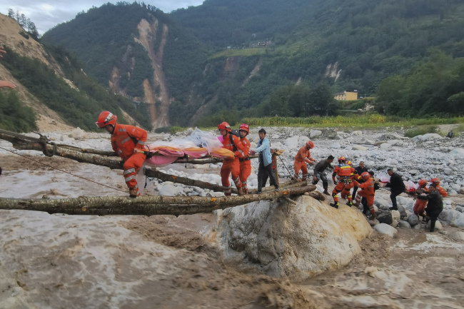 2022년 9월 지진이 발생한 중국 쓰촨성 간쯔장족자치주 루딩현에서 구조대원들이 통나무 다리 위로 부상자들을 들것에 실어 구조하고 있다./신화AP연합뉴