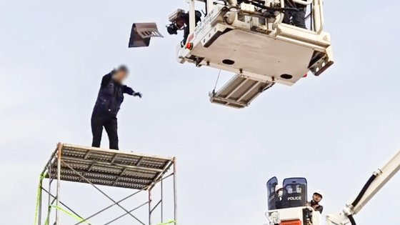 지난달 31일 오전 전남 광양시 포스코 광양제철소 인근 도로에서 높이 7ｍ 망루를 설치해 고공농성을 벌인 한국노총 금속노련 간부가 체포에 나선 경찰관에게 의자를 던지며 저항하고 있다. 연합뉴스.