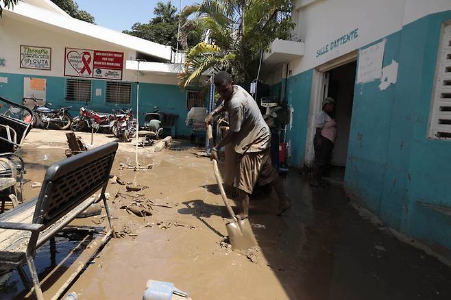 홍수로 큰 피해가 발생한 아이티 레오가뉴 지역의 한 병원 앞에서 직원이 지난 5일(현지시간) 물에 떠내려온 진흙을 퍼내며 청소를 하고 있다./AP연합뉴스