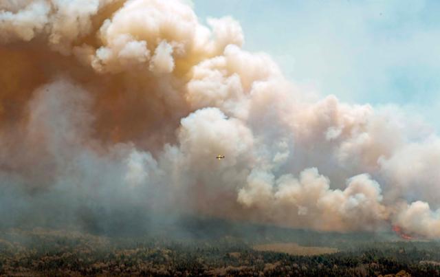 지난달 31일 캐나다 노바스코샤주 배링턴 호수 인근에서 산불로 인한 연기가 피어오르는 가운데 항공기가 날고 있다. 노바스코샤=AP 연합뉴스