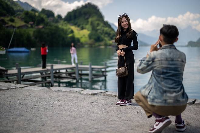 관광객이 지난 2일 스위스 알프스의 브리엔츠 호수 기슭에 있는 이젤발트 마을에 있는 한국 넷플릭스 시리즈의 유명한 부두 옆에서 사진을 찍고 있다. /AFP 연합뉴스