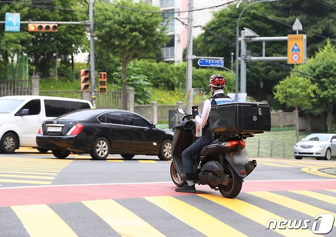 (용인=뉴스1) 김영운 기자 = 경기 용인시 기흥구 구갈초등학교 인근 어린이보호구역(스쿨존)에서 한 오토바이 배달기사가 정지선을 위반하고 있다. 2023.6.7/뉴스1  Copyright (C) 뉴스1. All rights reserved. 무단 전재 및 재배포 금지.