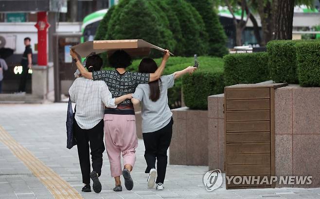 소나기는 피합시다! (서울=연합뉴스) 서울 명동 거리에서 시민들이 내리는 비를 종이상자로 가리고 발걸음을 옮기고 있다. 2023.5.18 [연합뉴스 자료사진]