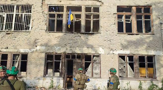 우크라이나 군인들이 11일(현지시간) 대반격으로 탈환했다고 주장하는 동부 도네츠크주 블라호다트네 마을의 한 건물에서 국기를 달고 있다. 로이터연합뉴스