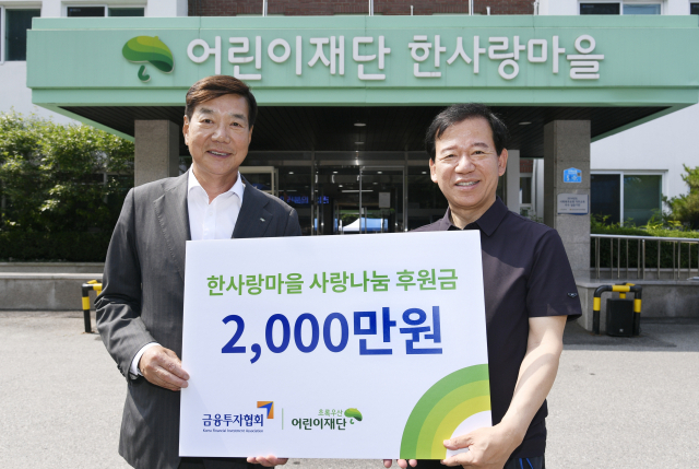 서유석(오른쪽) 한국금융투자협회장이 13일 경기 광주 한사랑마을에서 황영기 초록우산어린이재단 회장에게 기부금 2000만 원을 전달하고 있다. 사진제공=금투협