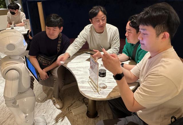 '우수사원 해외연수 프로그램'으로 일본을 방문한 LG유플러스 직원들이 카페 페퍼 팔러에서 활동하는 안내 로봇을 체험하고 있다. LG유플러스 제공