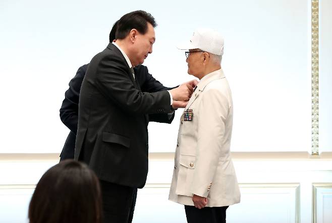 윤석열 대통령이 14일 청와대 영빈관에서 열린 국가유공자 및 보훈가족 초청 오찬에서 손희원 대한민국6.25참전유공자회 회장에게 '121879 태극기 배지'를 직접 달아주고 있다. 연합뉴스