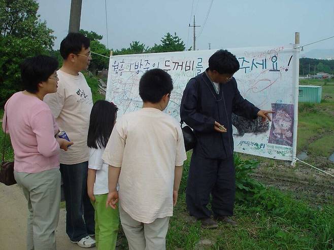 2003년 3월 어린이들이 원흥이방죽에 설치한 펼침막을 시민·어린이 등이 둘러보고 있다. 생태교육연구소 터 제공