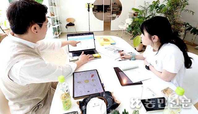 스튜디오에서 박신희 작가(왼쪽)가 기자에게 요새 인기 있는 이모티콘을 노트북으로 보여주고 있다.