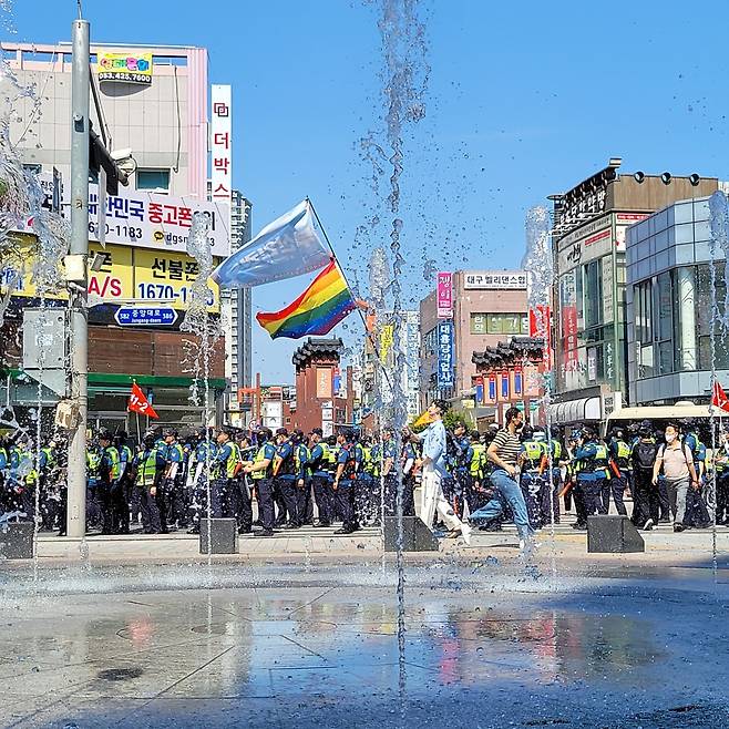 아수라장 속 무지개 깃발 (대구=연합뉴스) 대구퀴어문화축제가 열리는 17일 오전 주최 측의 대중교통전용지구 도로 사용 여부를 놓고 경찰과 행정 당국이 충돌하는 가운데 행사 참가자가 무지개 깃발을 들고 걸어가고 있다. 2023.6.17 [연합뉴스 김종운 촬영] sunhyung@yna.co.kr