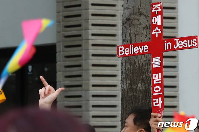 대구 중구 중앙로 대중교통전용지구 일대에서 열린 제14회 대구퀴어문화축제 참가자들이 도심을 행진하는 가운데 동성애를 반대하는 기독교 단체 관계자가 행진 구간 옆에서 십자가를 들어 보이고 있다. 2022.10.1/뉴스1 ⓒ News1 공정식 기자