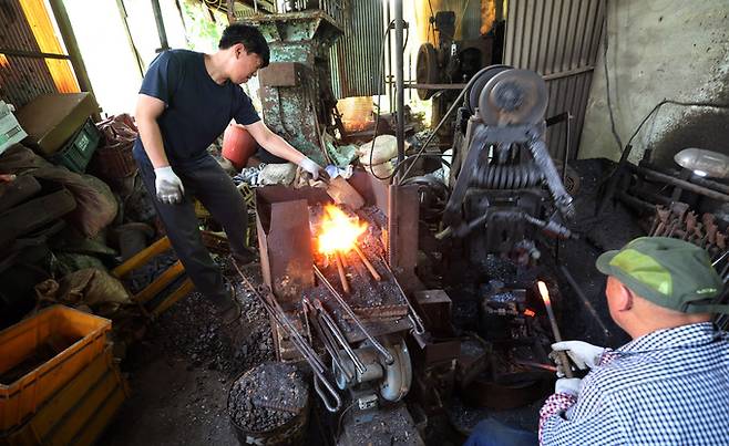 김원태 장인이 단조작업을 하는 사이 아들 김민규씨가 석탄을 채워 주고 있다. 끌을 만드는 첫 작업인 단조작업은 1000도의 고열 앞 단조기에서 하루 종일 일한다.