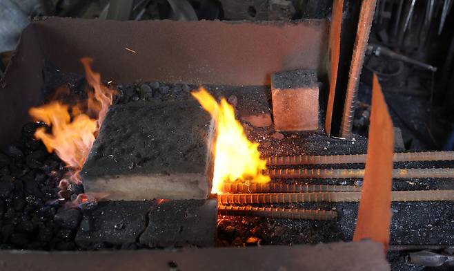 1000도가 넘는 고열의 가마에 철근을 달구어 날 모양을 만드는 단조작업을 하고 있다.