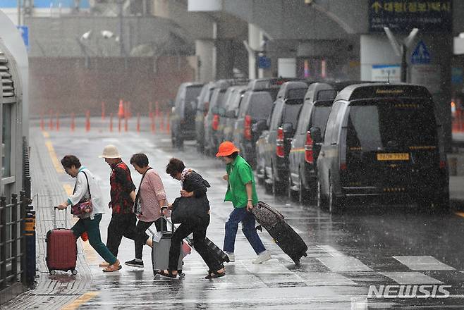 [제주=뉴시스] 우장호 기자 = 이번 주(26일~7월2일)는 장마 전선의 영향으로 전국 곳곳에 비 소식이 있겠다. 사진은 올해 첫 장맛비가 내린 지난 25일 오전 제주국제공항 1층 도착장에서 우산을 쓰지 않은 관광객들이 발걸음을 재촉하고 있는 모습. 2023.06.25. woo1223@newsis.com