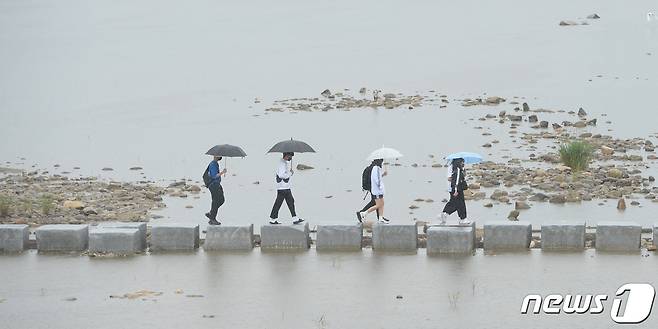 오랜 가뭄 끝에 반가운 단비가 내린 5일 경남 거창군 거창읍 위천천 징검다리에 우산을 쓴 주민들이 지나고 있다. (거창군 제공) 2022.6.5/뉴스1