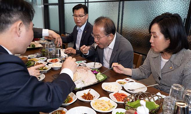 국민의힘 윤재옥 원내대표(가운대) 등 원내지도부가 지난 23일 서울 송파구 가락농수산물 종합도매시장 내 한 횟집에서 회 만찬을 하고 있다. 국민의힘 의원들은 최근 더불어민주당이 일본 후쿠시마 오염수 관련 여론전을 강화하는 데 대해 ‘횟집 가기 챌린지’ 등으로 대응하고 있다. 뉴스1