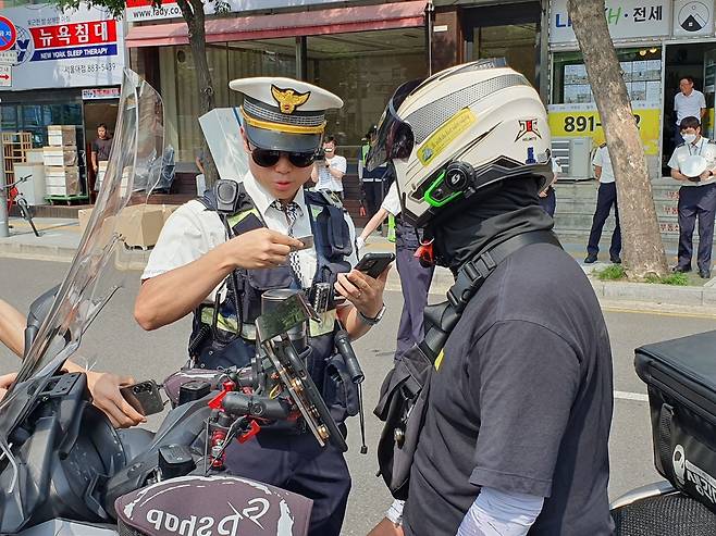 오토바이 운전자의 면허증을 확인하는 경찰 [촬영 최원정]