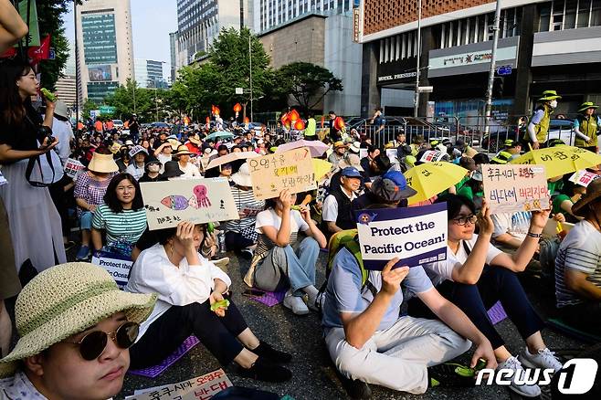 24일(현지시간) 한국 서울에서 일본 후쿠시마 제1 원자력 발전소 방사성 오염수 해양 방류에 항의하기 위해 모인 사람들이 "오염수를 육지에 보관하라＂는 팻말을 들고 있다. 2023.06.24/ ⓒ AFP=뉴스1 ⓒ News1 권진영 기자