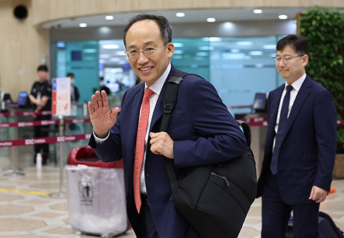 Deputy Prime Minister and Minister of Economy and Finance Choo Kyung-ho leaves Gimpo International Airport to attend the Eighth Korea-Japan Finance Ministers’ Meeting and raises his hand to reporters on the morning of June 29. [Photo by Yonhap]