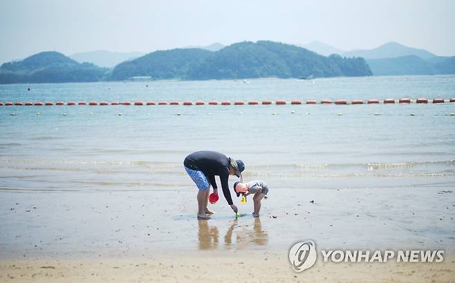 광암해수욕장 (창원=연합뉴스) 지난 6월 16일 경남 창원시 마산합포구 광암해수욕장에서 한 가족이 휴식을 취하고 있다. 가족의 모습 뒤로 입수 가능범위를 알려주는 해수욕장 통제선 부표가 보인다. 창원시는 올해 이 통제선 부표를 모래사장 쪽으로 더 가까이 조정하는 등 안전관리를 강화한다고 밝혔다. 2023.6.16 [연합뉴스 자료사진]