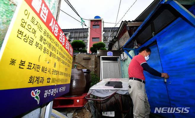 [광주=뉴시스] 이영주 기자 = 30일 오전 광주 북구 두암동 무허가 판자촌에서 이곳 거주민 심모(62)씨가 장마철 비 피해를 입은 자신의 집 대문을 걸어잠그고 있다. 2023.06.30. leeyj2578@newsis.com