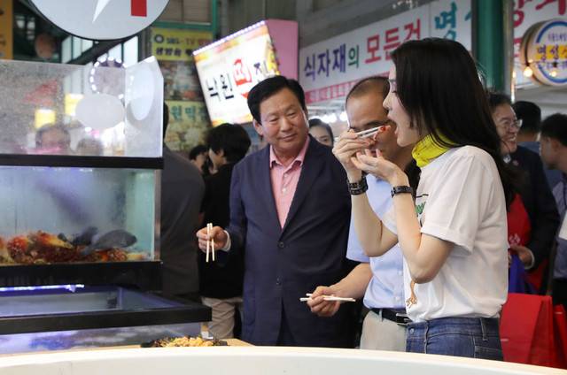 ▲ 김건희 여사가 3일 오후 강원도 강릉시 중앙·성남시장을 방문해 횟집에서 오징어회를 시식하고 있다. 2023.7.3 [대통령실통신사진기자단]