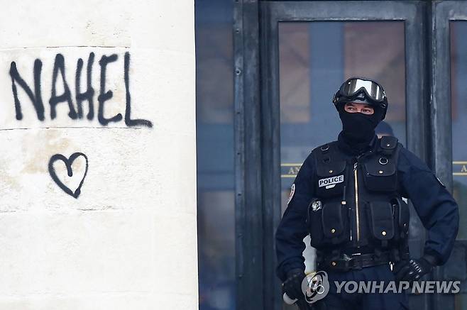 프랑스 낭트에서 경찰 총에 맞아 숨진 나엘 군의 이름이 적힌 벽 옆에 서 있는 경찰관 [AFP=연합뉴스 자료사진. 재판매 및 DB 금지]