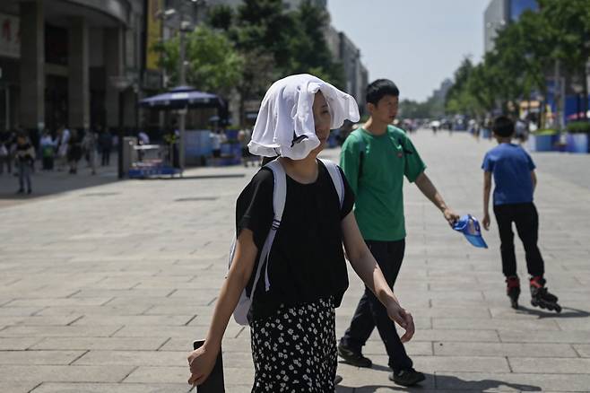 1일 중국 베이징에서 한 여성이 열기를 막기 위해 흰 옷을 머리 위에 얹은 채 거리를 걷고 있다./AFPBBNews=뉴스1