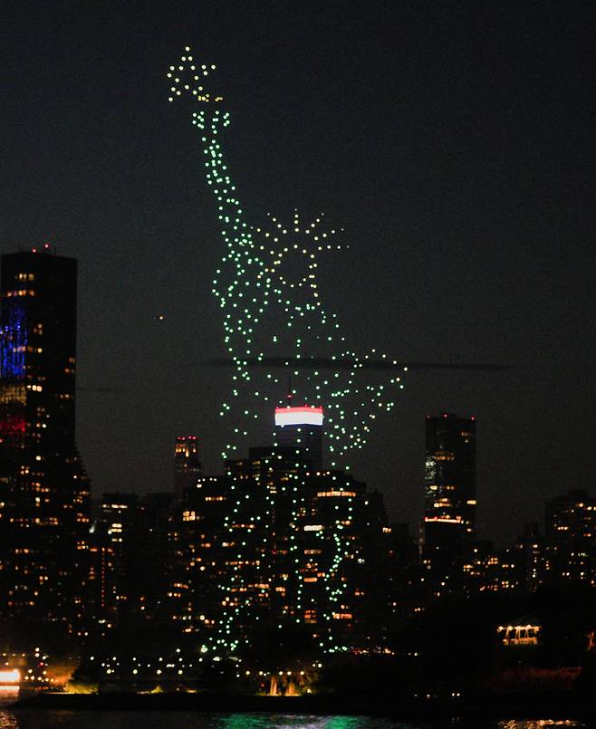 2023년 7월 4일 미국 뉴욕에서 사람들이 미국 독립기념일을 축하하는 가운데 드론이 형형색색의 불빛으로 자유의 여신상 모양을 만들고 있다./로이터 연합뉴스