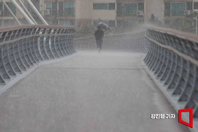 강한 장맛비가 쏟아지고 있는 11일 서울 이화교에서 한 시민이 우산을 쓰고 이동하고 있다. 사진=강진형 기자aymsdream@