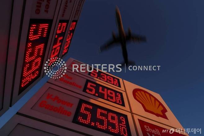 An aircraft flies over a sign displaying current gas prices as it approaches to land in San Diego, California, U.S., February 28, 2022. REUTERS/Mike Blake/File Photo