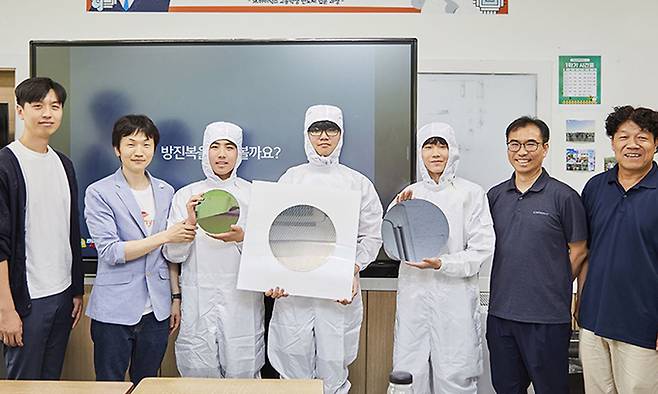 지난달 27일 경기 수원시 삼일공업고에서 열린 SK하이닉스의 오프라인 특강에서 학생들이 방진복 차림으로 웨이퍼를 들고 포즈를 취하고 있다. SK하이닉스 뉴스룸 제공