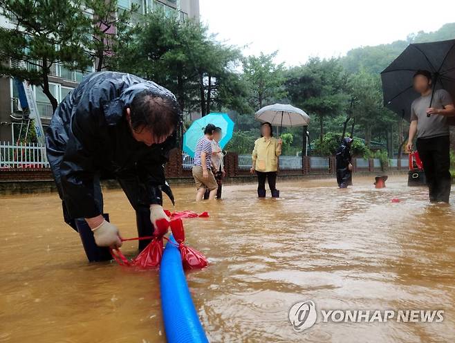 14일 전북 군산시 구암동 한 상가 건물 인근 도로가 이틀째 내린 집중호우로 침수돼 공무원과 주민들이 배수 작업을 하고 있다.[연합]