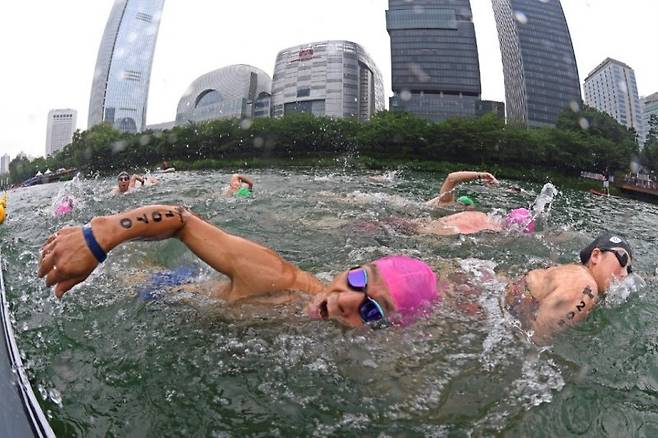 롯데월드타워가 16일 개최한 도심 속 이색 스포츠 대회 '2023 롯데 아쿠아슬론(Aquathlon)'에서 참가자들이 롯데월드타워와 석촌호수를 배경으로 힘차게 수영하고 있다. 롯데물산 제공